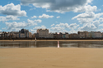 Fototapeta premium View of the promenade and the beach with wooden breakwaters at low tide on a sunny summer day, Saint-Malo, Brittany, France