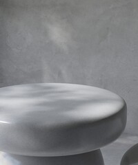 Glossy smooth round gray stone podium table in dappled sunlight on polished cement concrete wall...