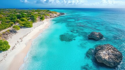 Obraz premium Aerial view of a serene tropical beach with turquoise waters and rocky formations under a clear sky
