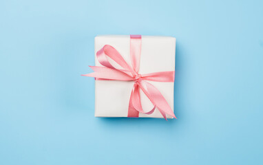 White gift box with pink bow on blue background.