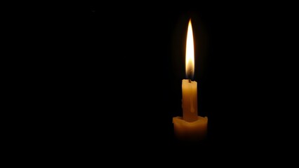 Fototapeta premium A candle burning in the dark
