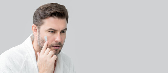 Fototapeta premium Caucasian beauty man use moisturizing face balm for healthy skin, male skincare concept. Male beauty skin care portrait. Healthy clean face after shaving, facial treatment, banner poster, copy space.