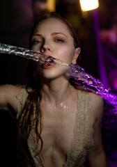 A sexy woman posing at night with city lights. Woman mouth with water drops. Wet lips with water. A...