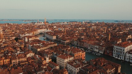 Obraz premium Aerial view of Venice’s red rooftops and canals, bathed in the warm glow of dusk, capturing the charm of the floating city.