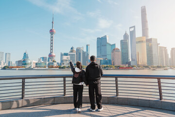 Couple traveler visiting in Shanghai, China. Tourists sightseeing Shanghai view of Lujiazui on The Bund of Shanghai. landmark and popular for tourism attractions. Vacation concept