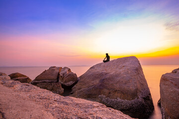 Man Sitting Relax On The Rocks By The Sea At Twilight Time Watching Beautiful Sky After Sunset, Long Exposure