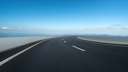 Scenic Curved Road with Open Sky and Mountains in the Background