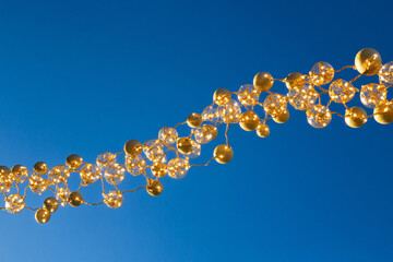 Brightly colored string lights hang against a clear blue sky, creating a cheerful and festive atmosphere in the evening. The lights shimmer and reflect joy