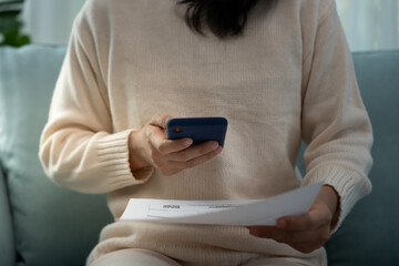 woman use phone scan barcode or QR codes to pay credit card bill after receiving document invoice....