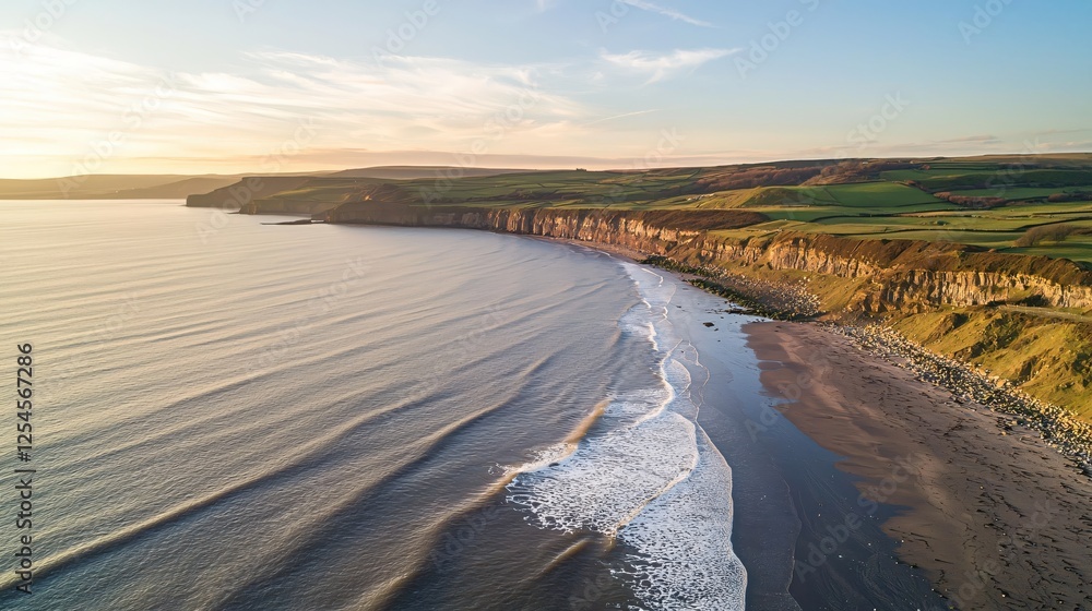 Poster Aerial View of Coastal Cliffs and Tranquil Beach at Sunset with Rolling Waves and Green Fields