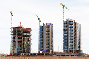 High-rise buildings under construction in Tempe, Arizona, featuring multiple tower cranes, glass...