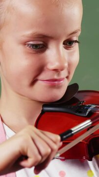 Schoolgirl playing violin in classroom at school