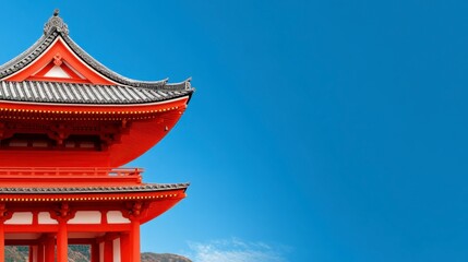 Architectural detail of a vibrant red Japanese pagoda style building against a clear, vibrant blue sky. The structure's intricate roof design and the
