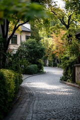 Cobblestone road curves in residential area with green trees for real estate
