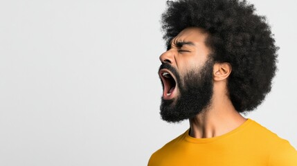 Man with curly hair yawning against a light background during daytime