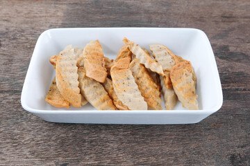 Fried pork sausage in a white ceramic plate on a wooden table.
