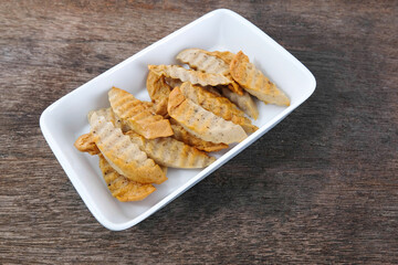 Fried pork sausage in a white ceramic plate on a wooden table.