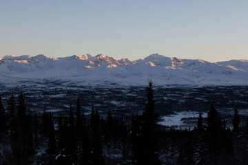 Sun on mountaintop on winte afternoon in Alaska.