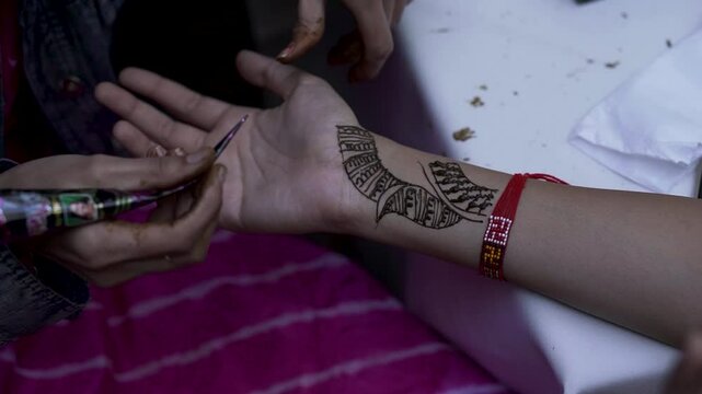 Close up of Mehandi artist applying traditional Henna design on woman's pal