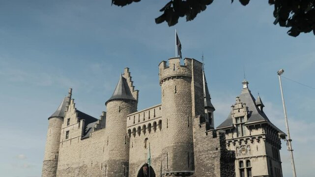 Historic Het Steen castle in Antwerp, Belgium, framed by tree branches, showcasing its medieval architecture