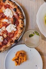 Pizza napolitana con burrata y pasta en mesa gourmet
