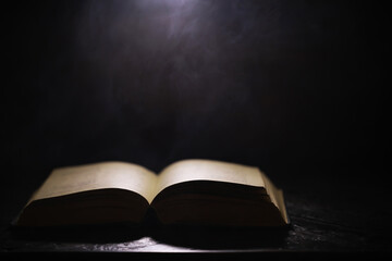Open Book in Dim Light with Mystical Smoke, Dark Background Creating Enigmatic and Mysterious Atmosphere