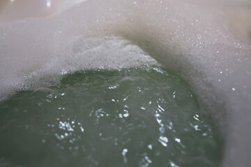 Relaxing Bubble Bath with Foam and Soothing Green Water in Cozy Bathroom Close-up