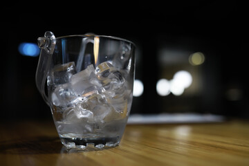 Close-Up of Ice Cubes in a Transparent Glass on Wooden Table with Bokeh Background