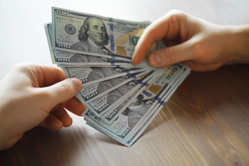 Exchanging Hundred Dollar Bills Between Hands on a Wooden Surface