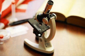 Vintage Microscope on Wooden Desk Amidst Laboratory Equipment and Open Book
