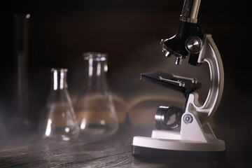 Vintage Microscope with Laboratory Glassware on Wooden Table in Science Lab