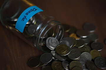 Spilled Donation Jar with Coins: Financial Support Concept and Charitable Giving
