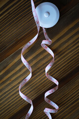 Rolled White Measuring Tape on Wooden Background Unraveling