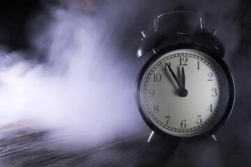 Vintage Alarm Clock Amidst Misty Fog on Wooden Surface at Midnight