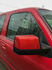 Close-Up of a Red Pickup Truck's Side Mirror and Window with Raindrops, Capturing a Rainy Day Automotive Scene