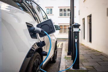 Electric car plugged in and changing on urban city street