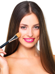 Fototapeta premium Girl, makeup brush and smile in studio with foundation, portrait and application by white background. Woman, model and person with cosmetics, beauty and tools for facial transformation in Portugal