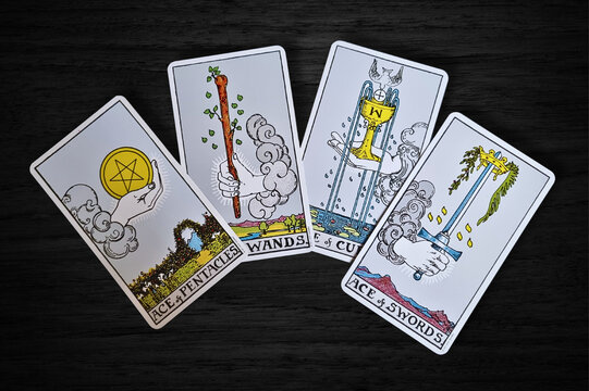 Les As des suites du Tarot du jeu Rider-Waite, pos&eacute;e sur un fond en bois sombre. Elles repr&eacute;sentent de nouveaux d&eacute;parts, des opportunit&eacute;s et des &eacute;nergies brutes dans chaque &eacute;l&eacute;ment du tarot. 