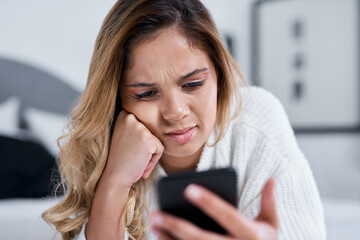 Woman, phone and confused on bed, reading or texting notification with web chat at apartment....