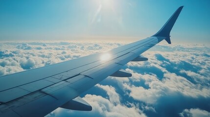 Obraz premium High angle view of aircraft wing over fluffy clouds, bright sunlight shining through the wing, serene atmosphere, sunny day, aerial perspective