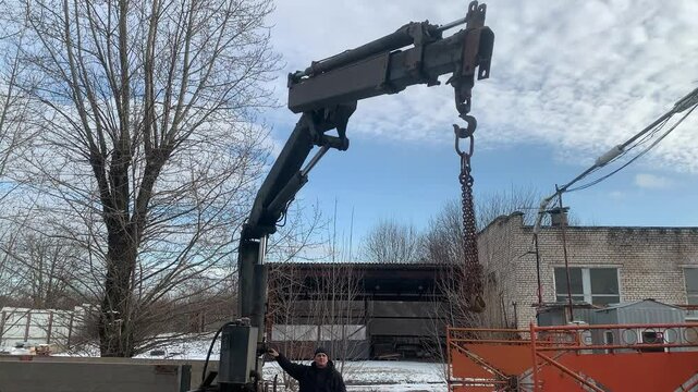 Construction worker operating crane mounted on a truck.