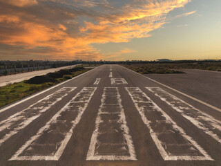 Fototapeta premium Perspective view of a small airstrip in a rural area at sunset, narrowing from the runway head