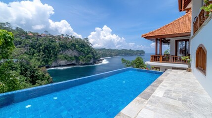 Fototapeta premium Ocean view infinity pool on a cliff overlooking a tropical landscape, featuring a clear blue pool, stone patio, wooden deck, and lush green hillside