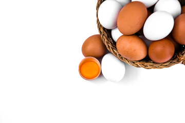 brown and white chicken eggs in a wicker basket on a white background