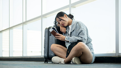 An unhappy, bored Asian female passenger waiting for her delayed flight.
