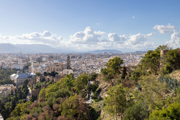 Photo of the streets of the city of Malaga in Spain showing an aerial view of the city centre with the high rise apartments and mountains in the background on a sunny day in the month of January