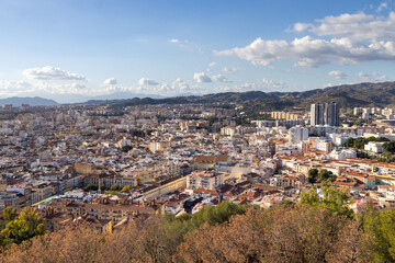 Photo of the streets of the city of Malaga in Spain showing an aerial view of the city centre with the high rise apartments and mountains in the background on a sunny day in the month of January