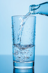Crystal clear water being poured into a transparent glass, creating refreshing ripples and bubbles