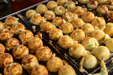 Cooking Delicious Takoyaki on a Grill with Wooden Sticks