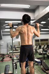 Asia Man's back with muscle in pull-up gym machine	